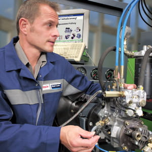 un technicien de bosch travaillant sur un moteur diesel.